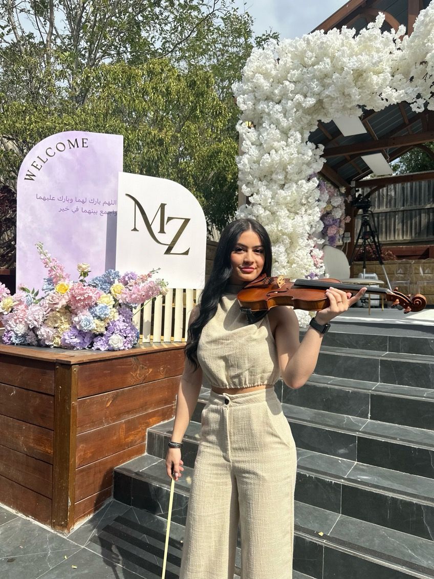 Sofia Luppino at a wedding reception holding a violin.