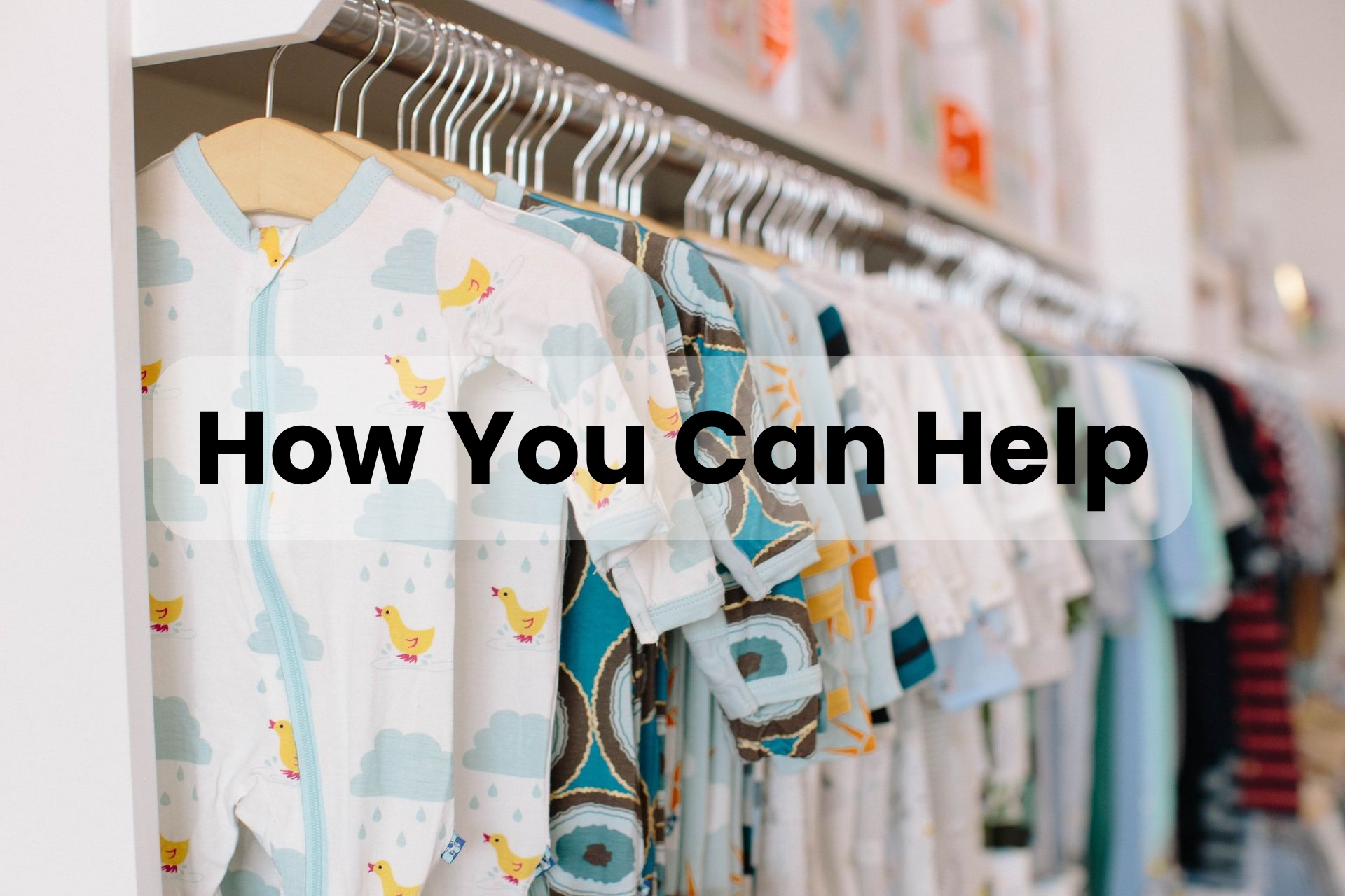 A row of baby clothes hanging on a rack in a store.