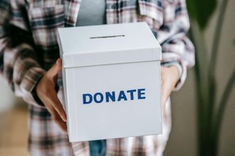 A person is holding a white box that says `` donate ''.