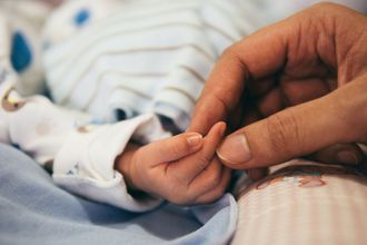 A close up of a person holding a baby 's hand.