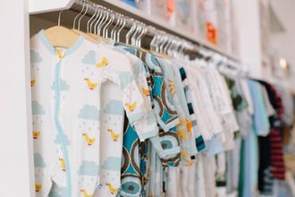 A row of baby clothes hanging on a rack in a store.