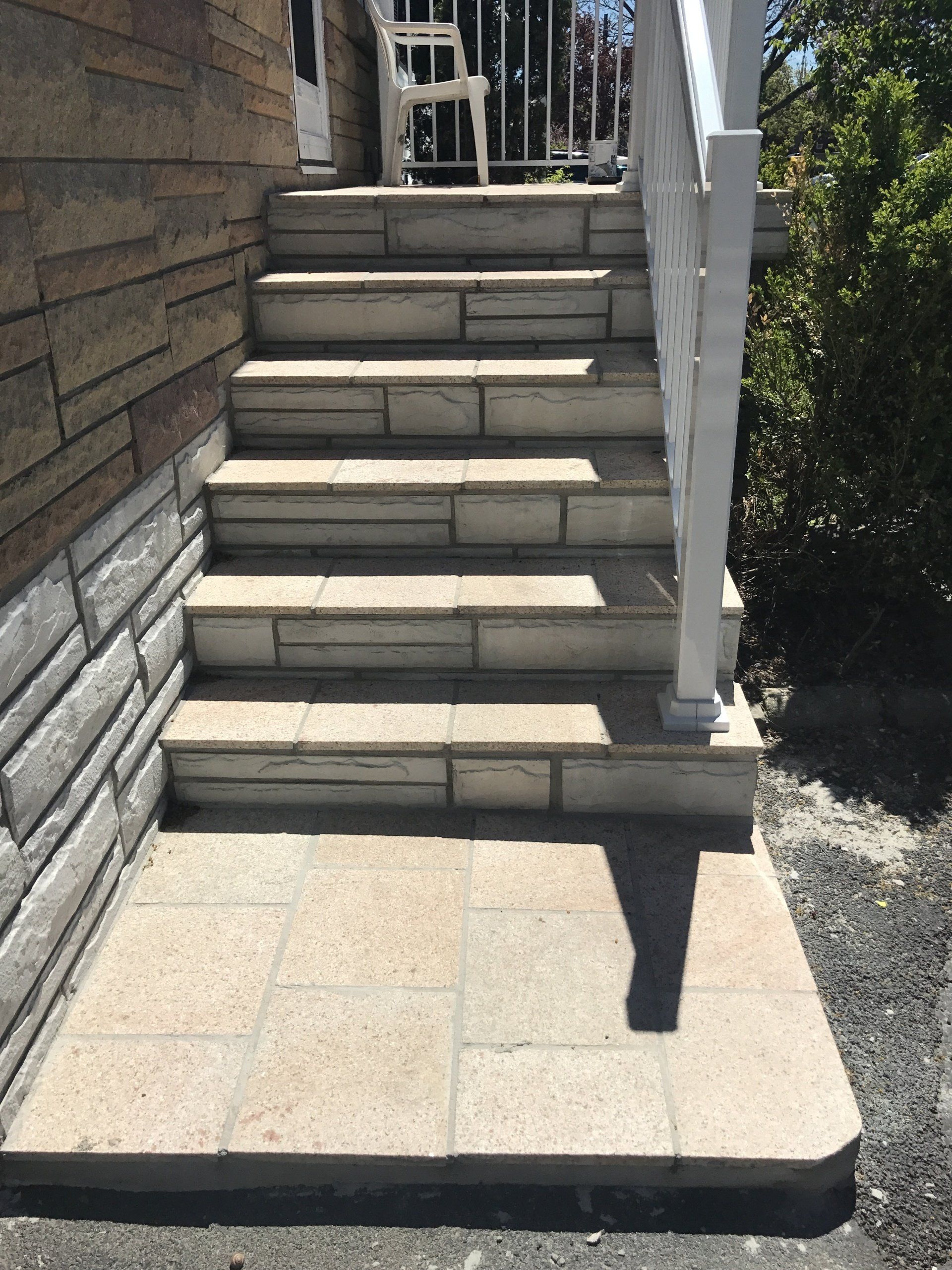 A set of stairs leading up to a house with a white railing
