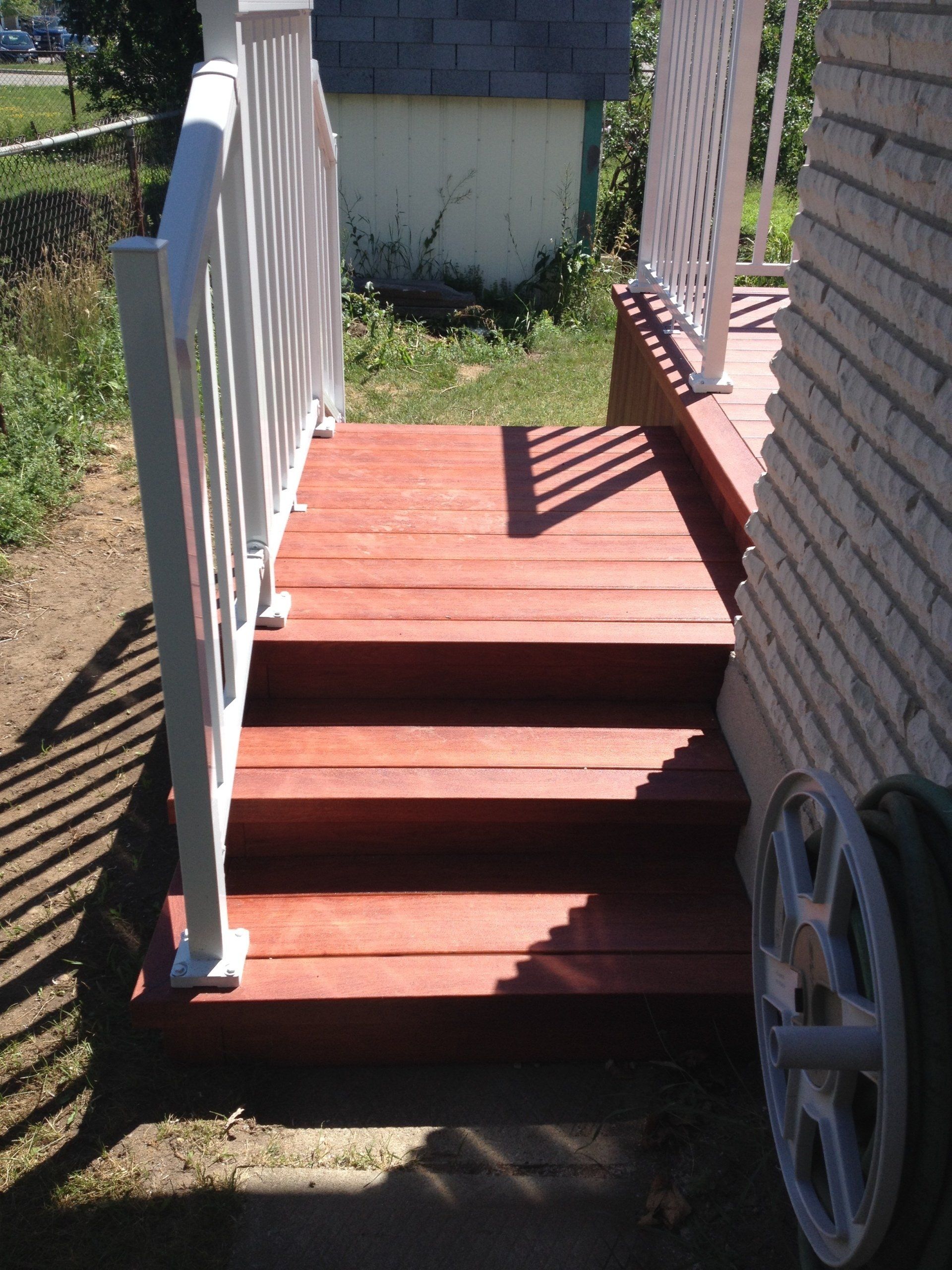 A wooden deck with stairs and a white railing