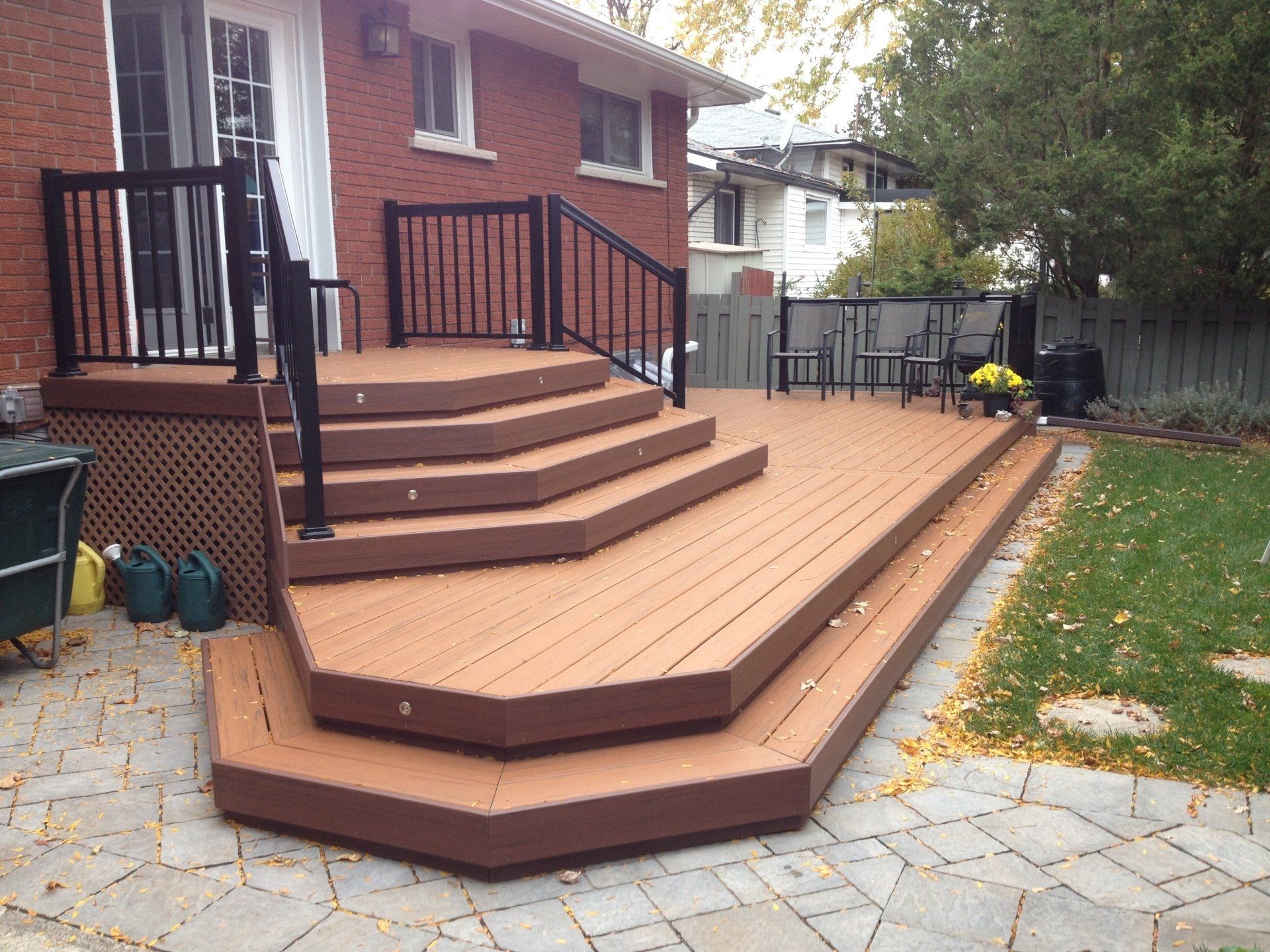 A wooden deck with stairs and a railing in front of a brick house