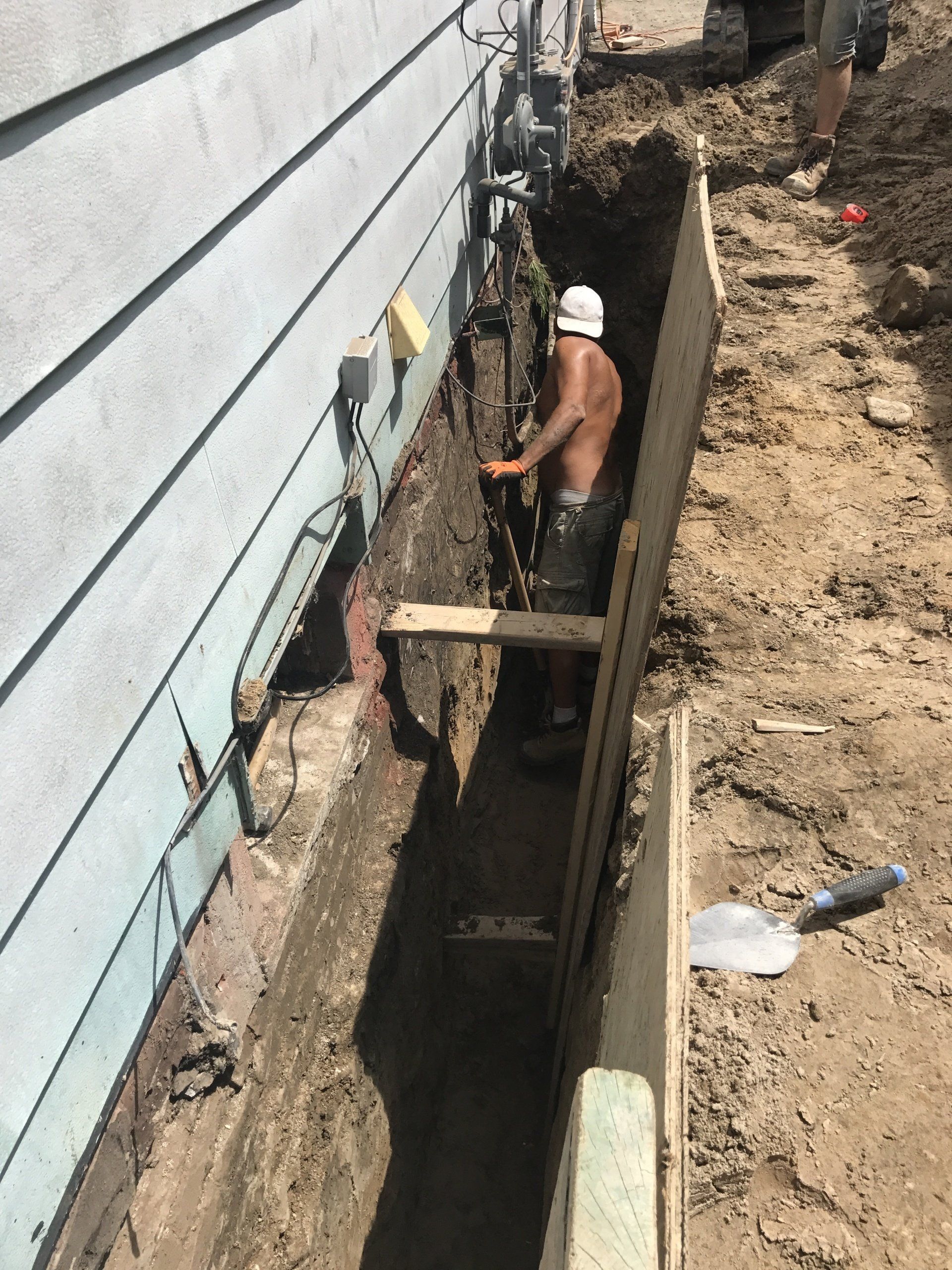 A man is digging a hole in front of a house.