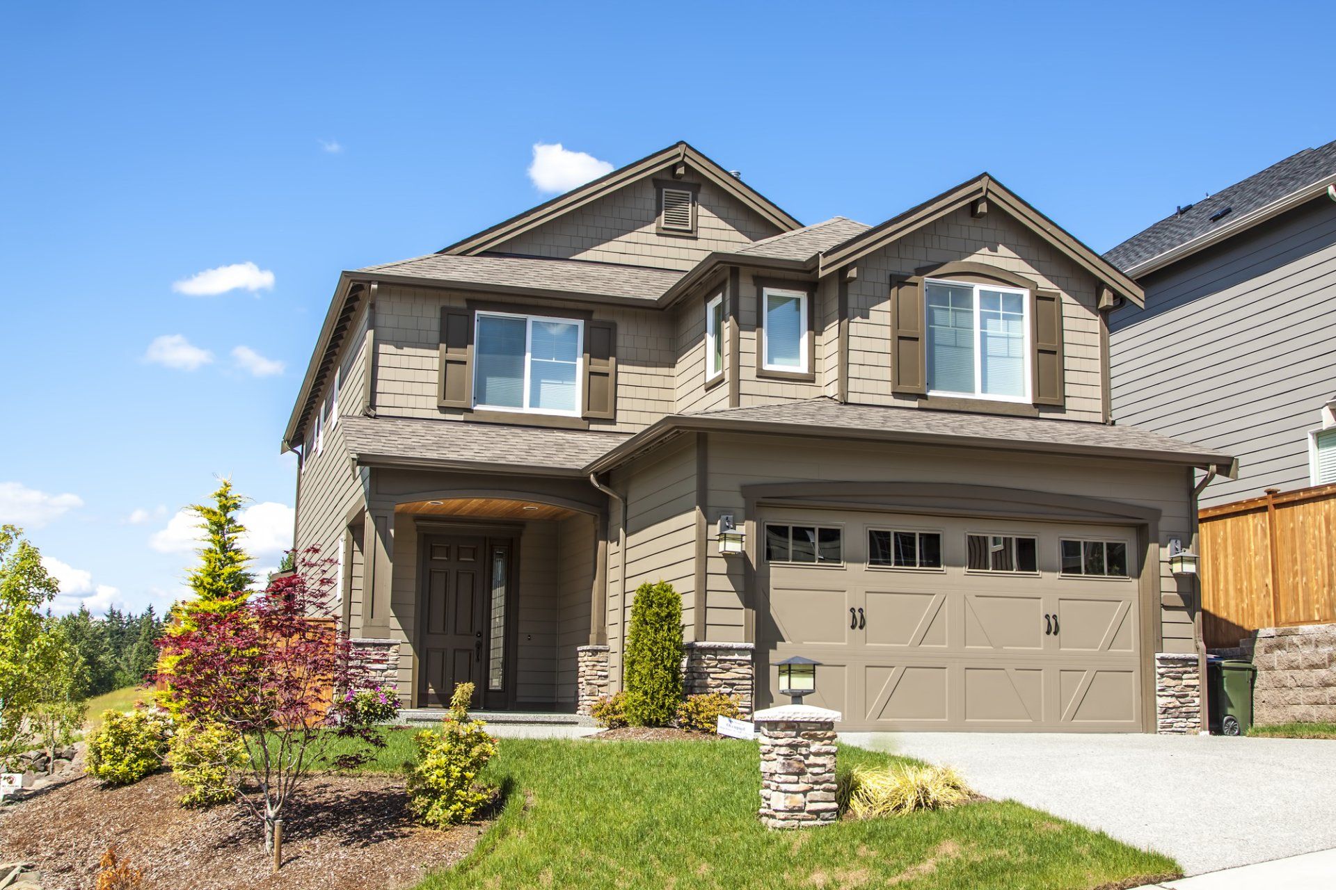 A large house with a large garage and a fence in front of it.