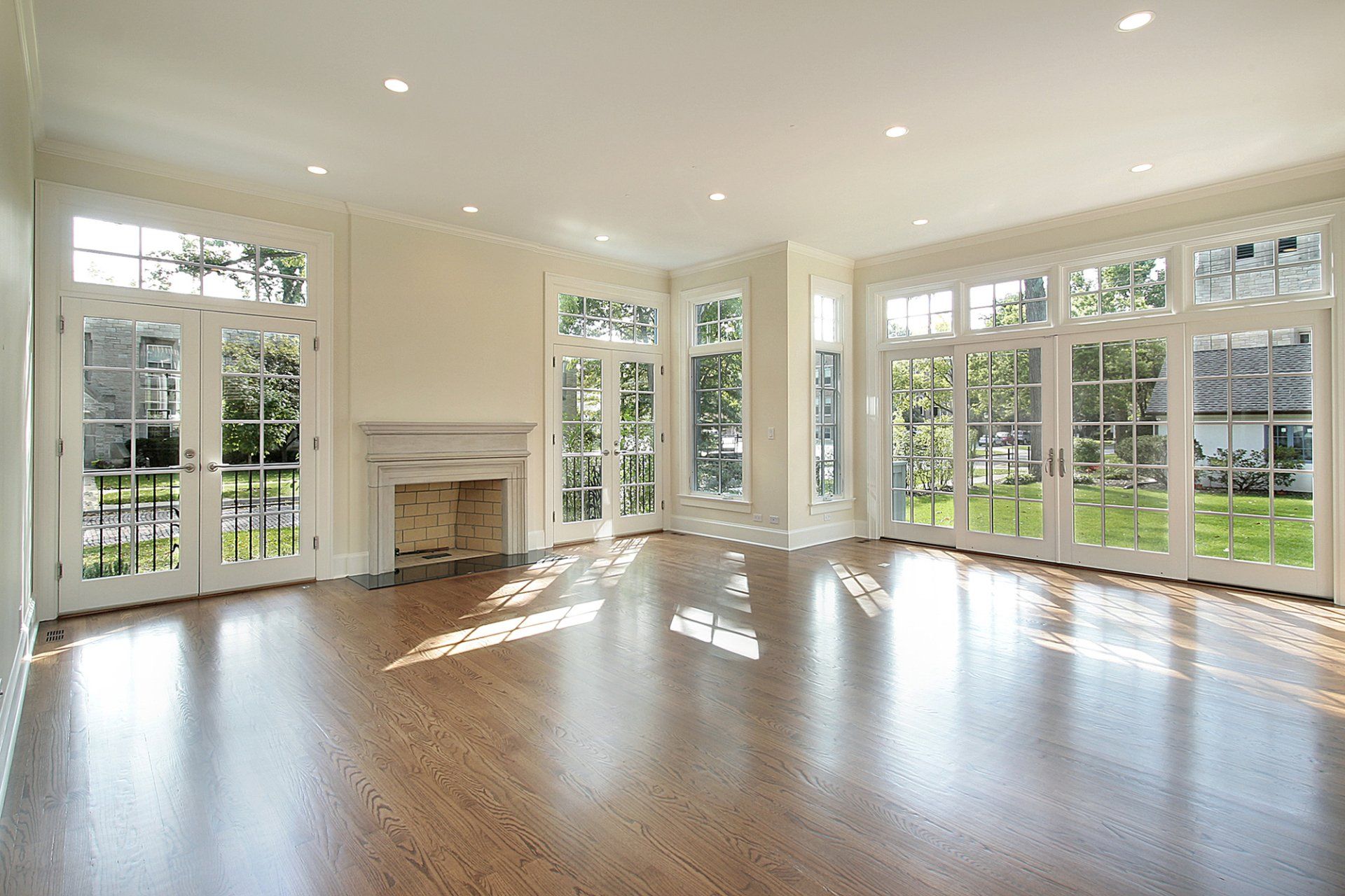 An empty living room with hardwood floors , a fireplace , and lots of windows.