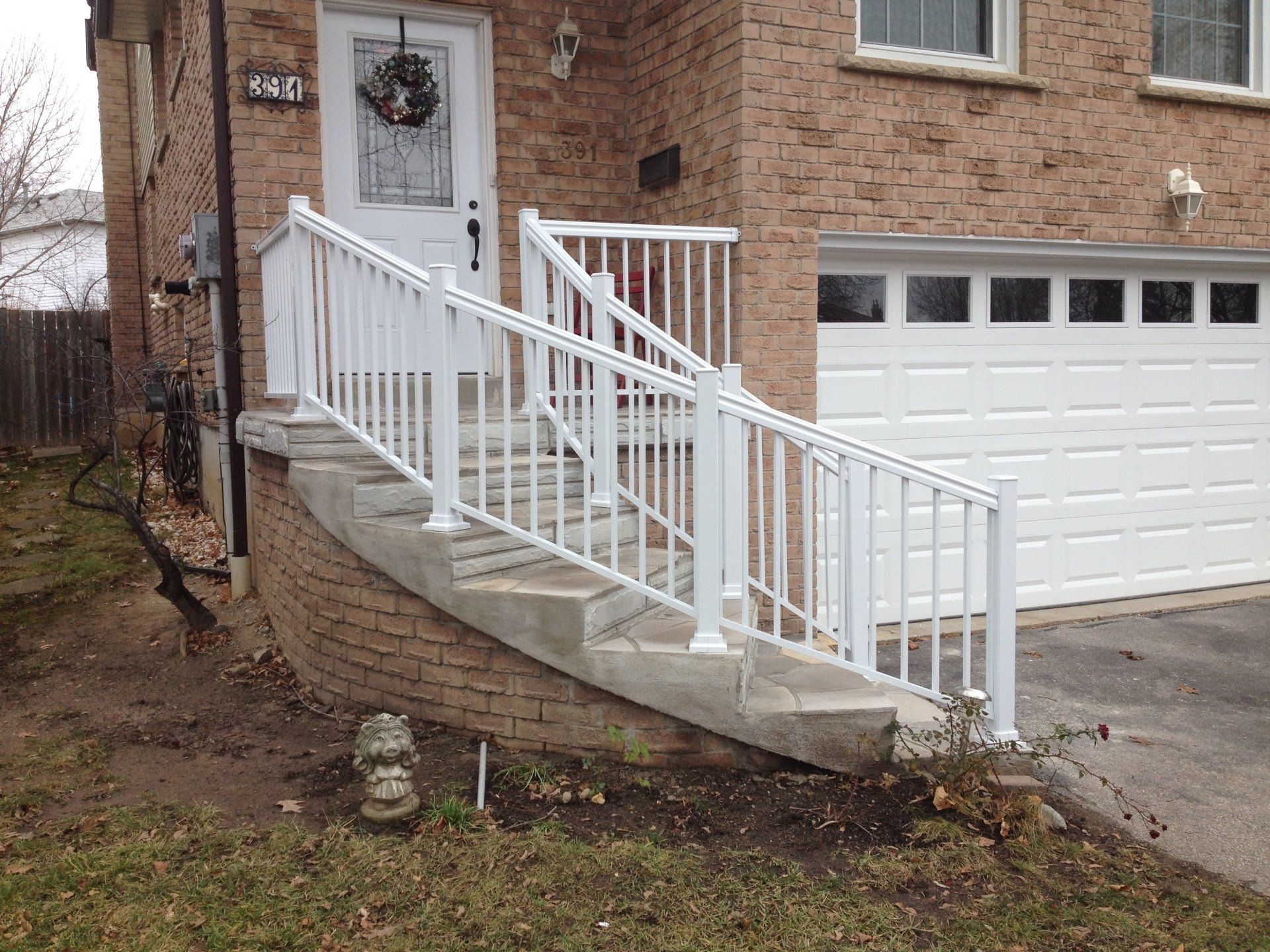A brick house with a white railing and stairs