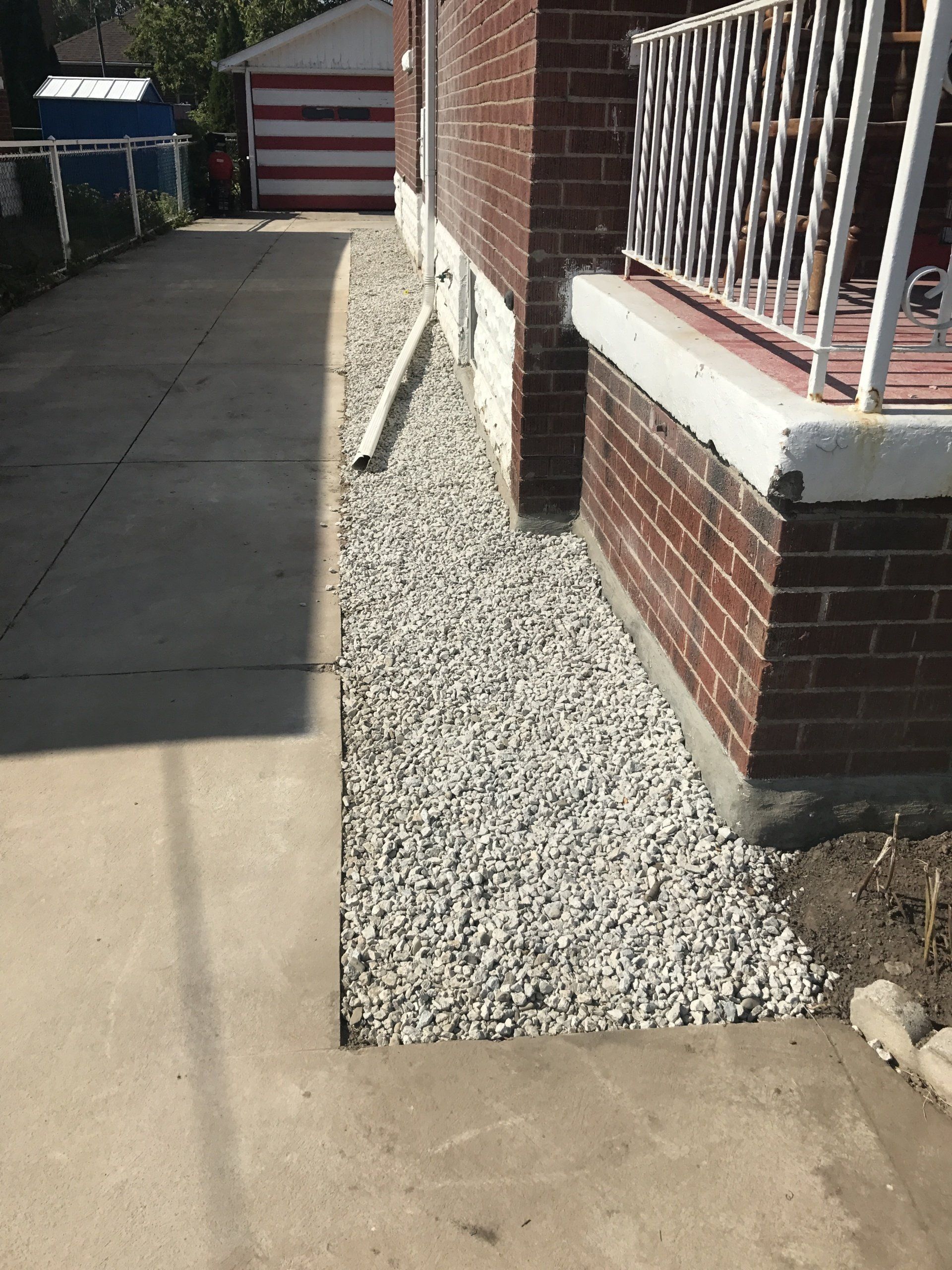 A brick house with a sidewalk and gravel in front of it.