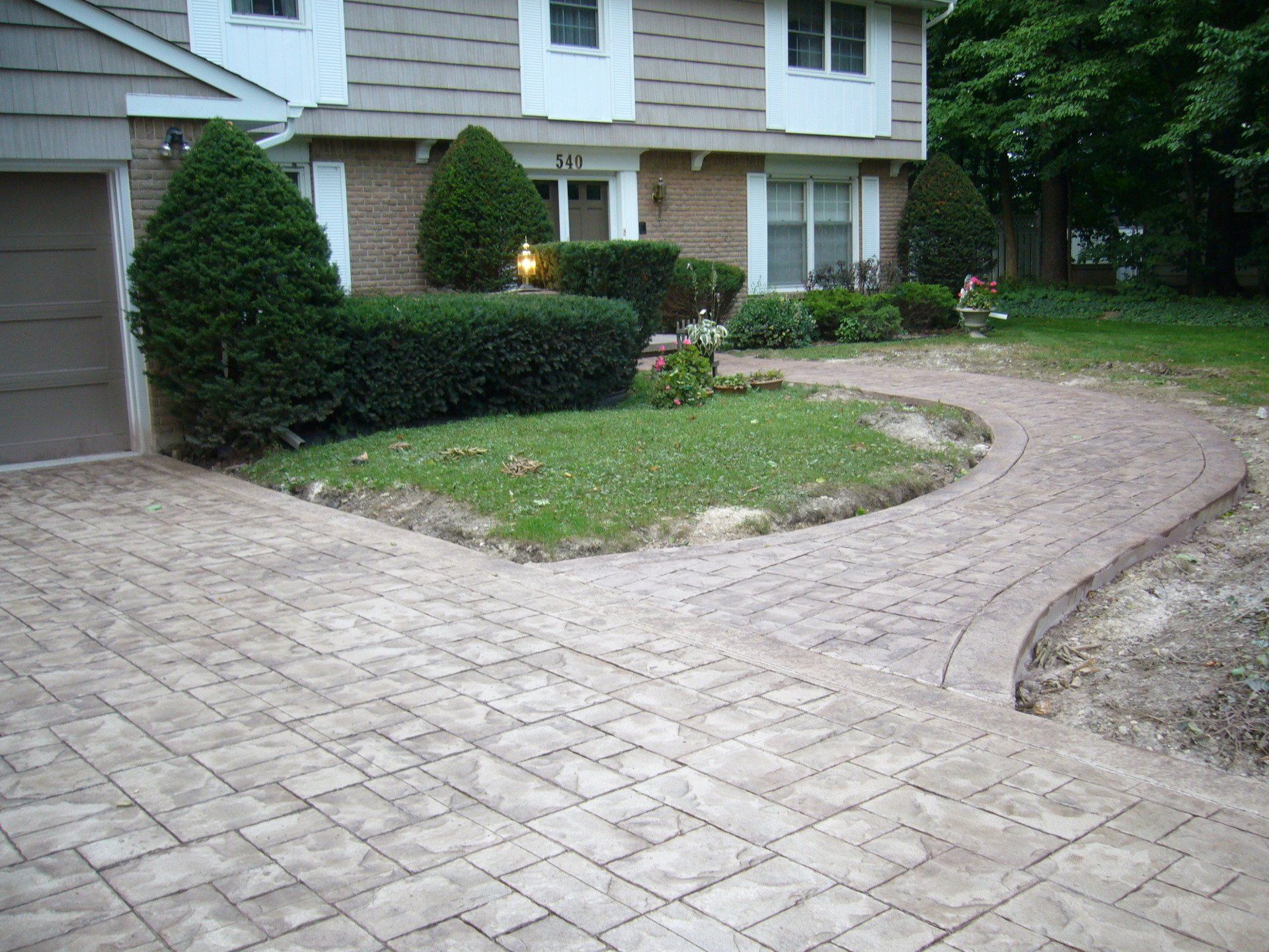 A brick driveway leading to a house with a garage