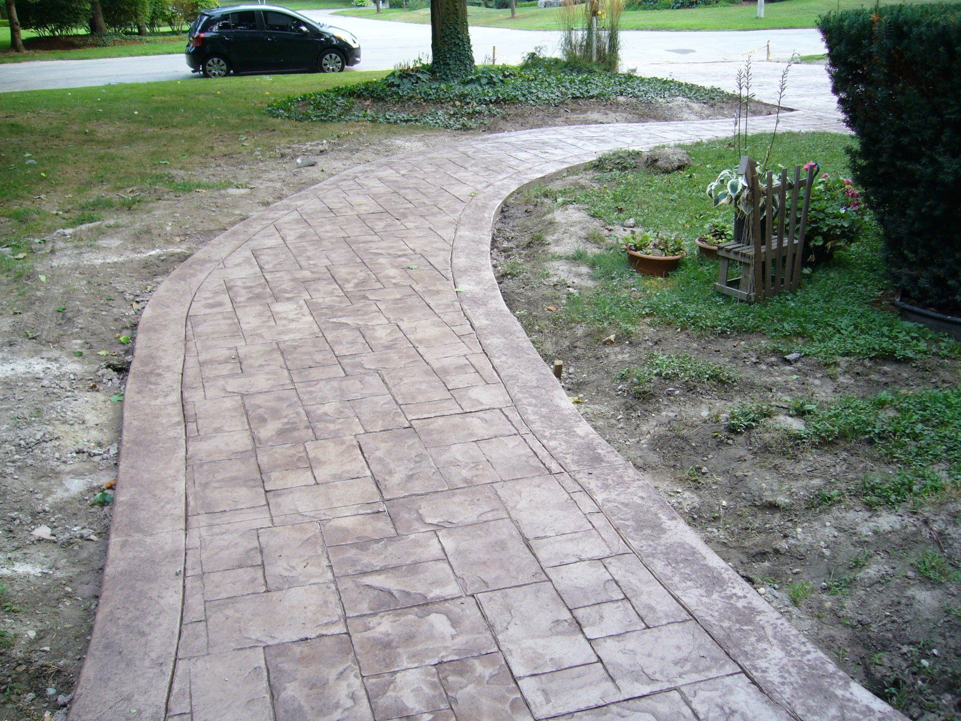 A brick walkway with a car parked on the side of it