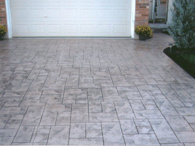 A brick driveway with a white garage door in the background