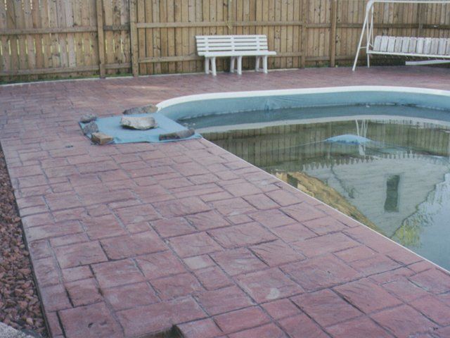 A brick walkway leading to a swimming pool