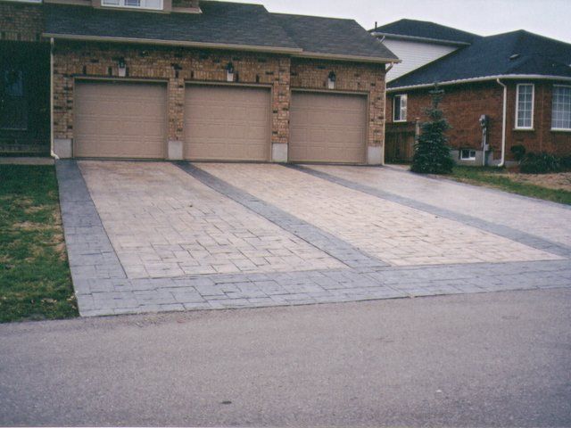 A driveway in front of a house with three garage doors