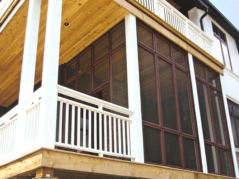 A screened in porch with a white railing and lots of windows