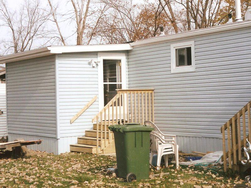 A mobile home with a green trash can in front of it