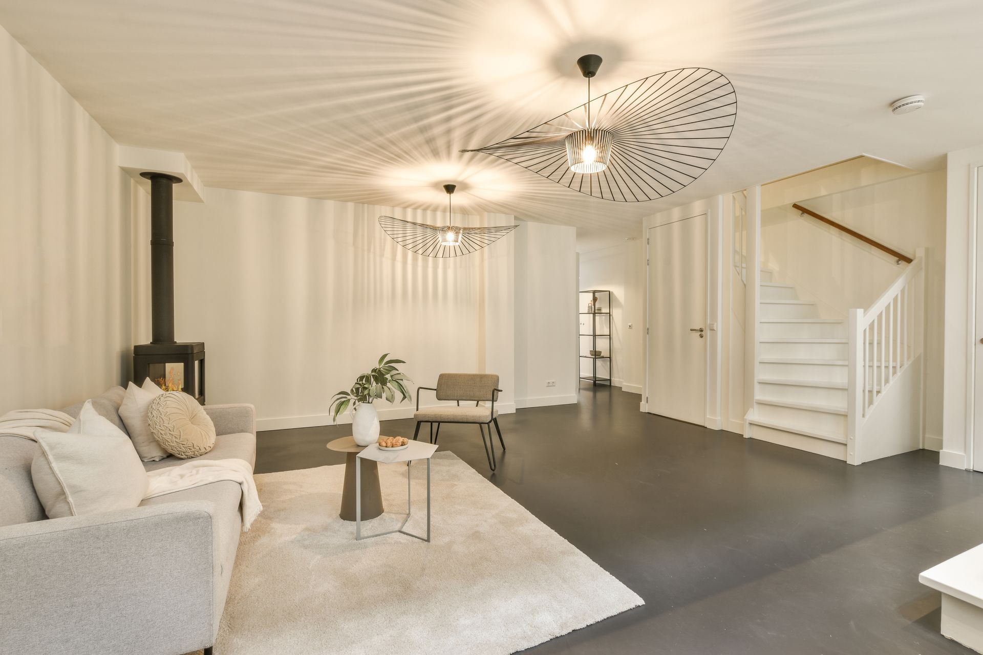 A living room with a couch , chair , table and stairs.