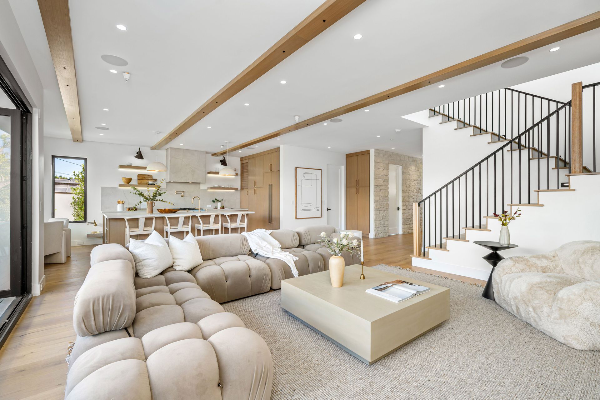 A living room with a couch , coffee table , chairs and stairs.