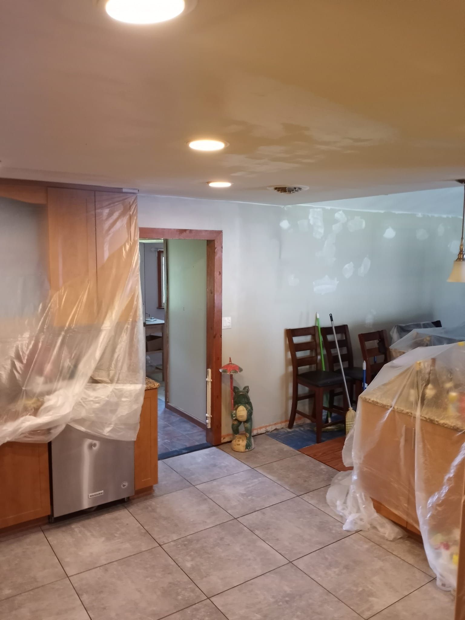 A kitchen and dining room are being remodeled and covered in plastic.