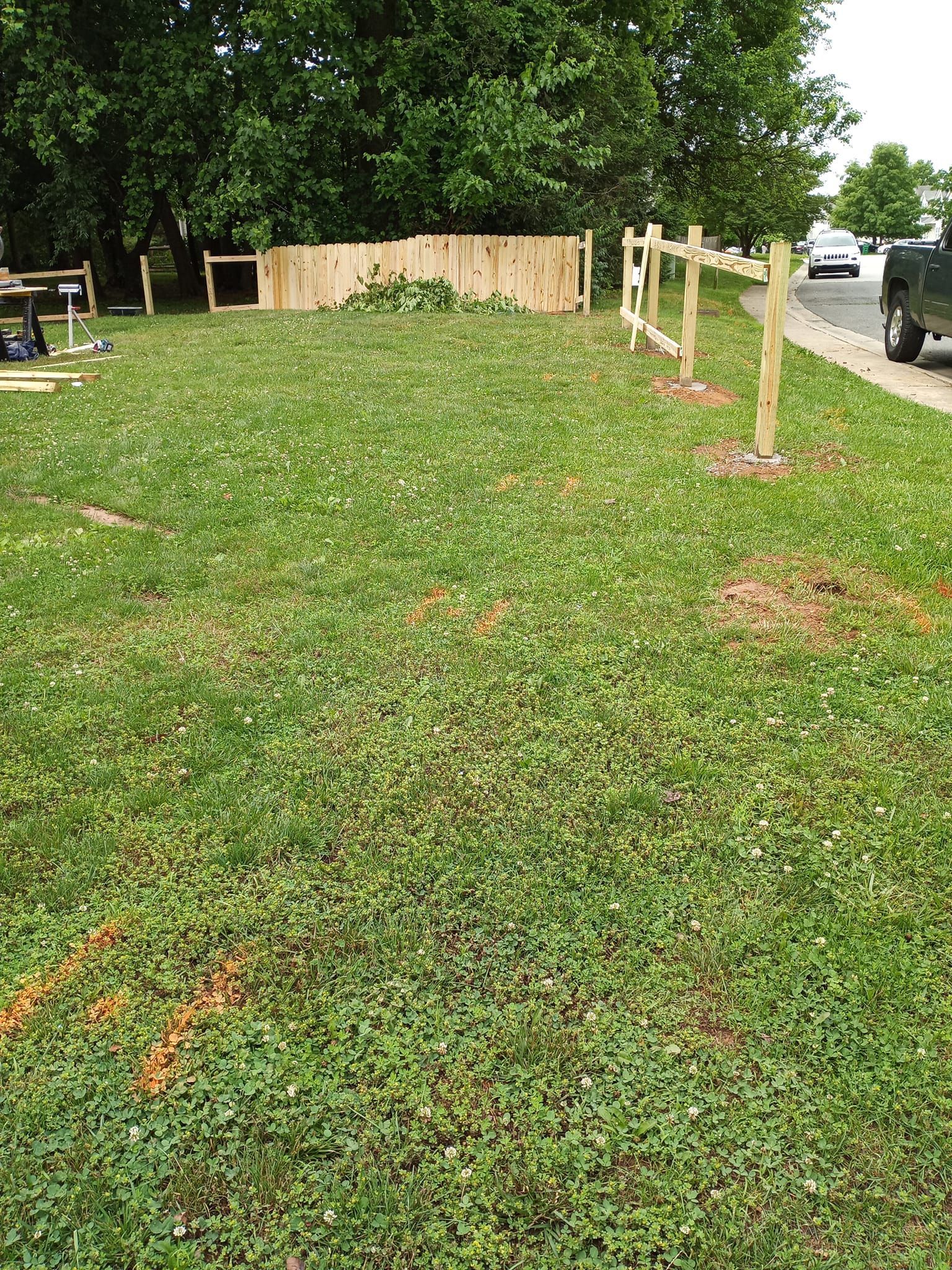 A large lush green field with a wooden fence in the background.