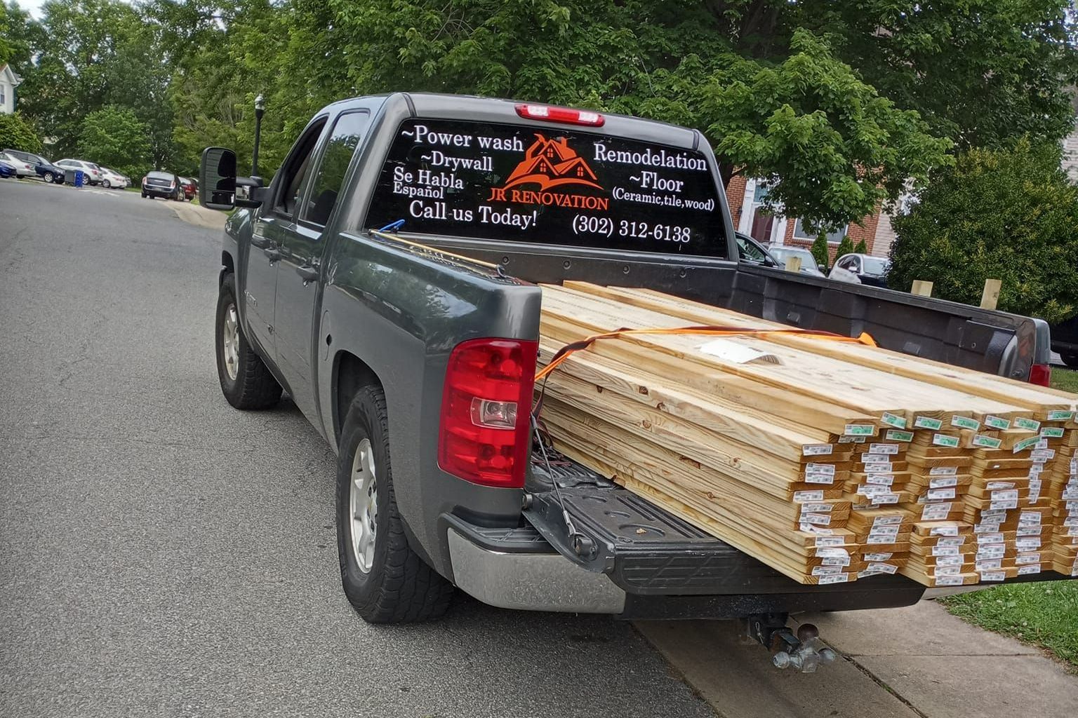 A truck with a stack of wood in the back is parked on the side of the road.