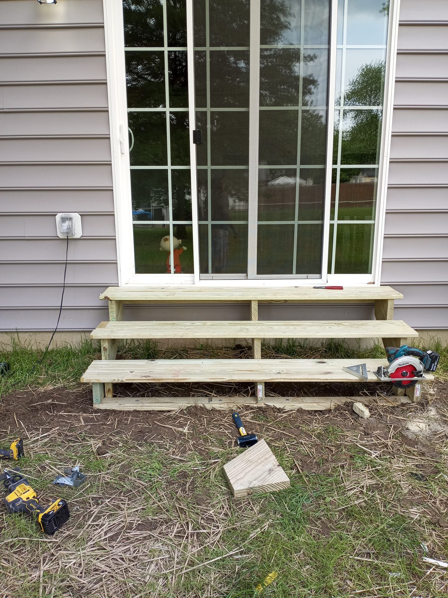 A wooden staircase is being built in front of a sliding glass door.