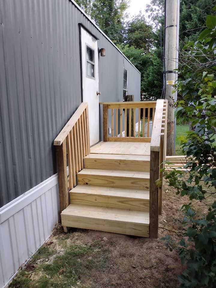 A wooden deck with stairs leading up to a mobile home.