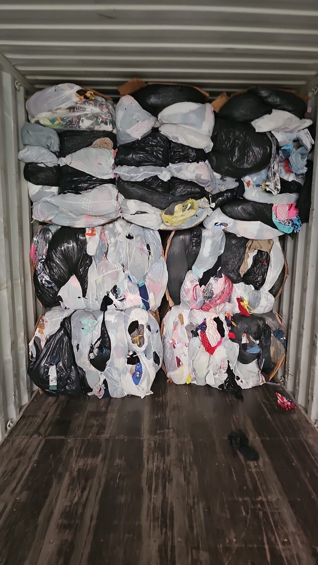 A container filled with lots of trash bags and clothes.