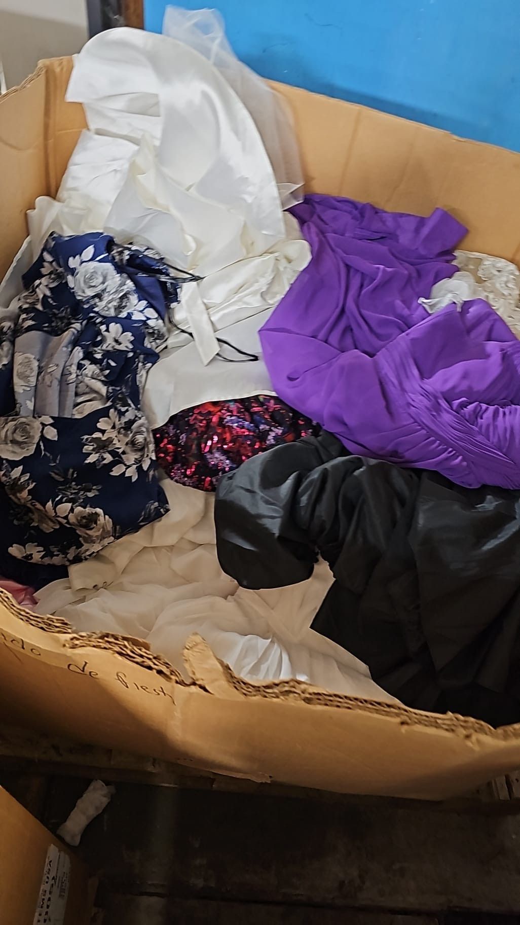 A cardboard box filled with clothes and a purple scarf.