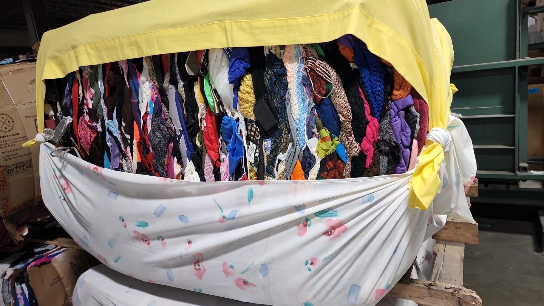 A pile of clothes wrapped in plastic is sitting on top of a wooden pallet.