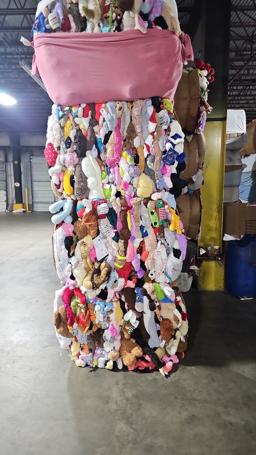 A pile of stuffed animals are stacked on top of each other in a warehouse.