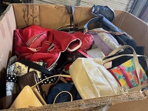 A cardboard box filled with lots of handbags and shoes