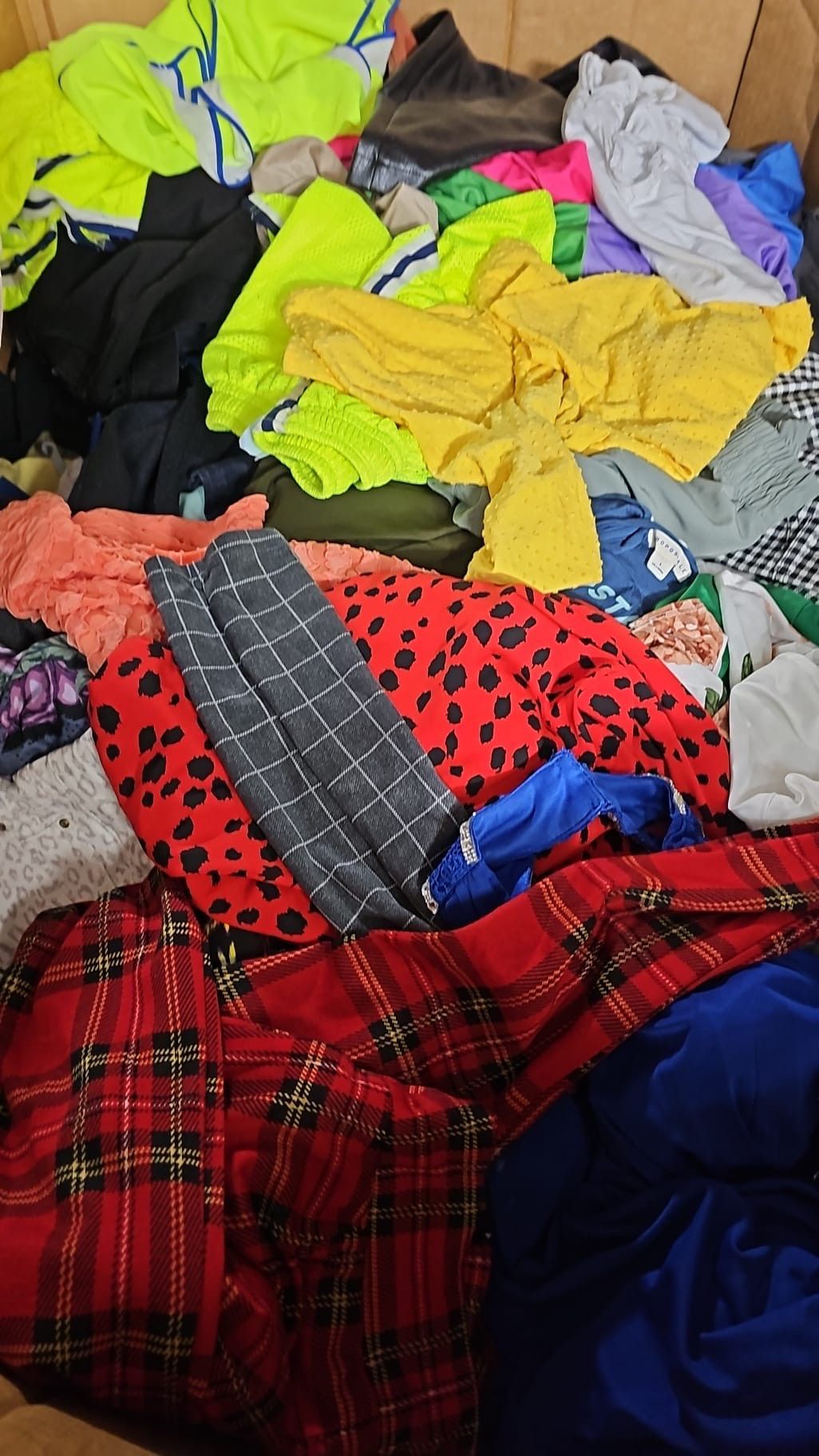 A pile of colorful clothes is laying on a bed.