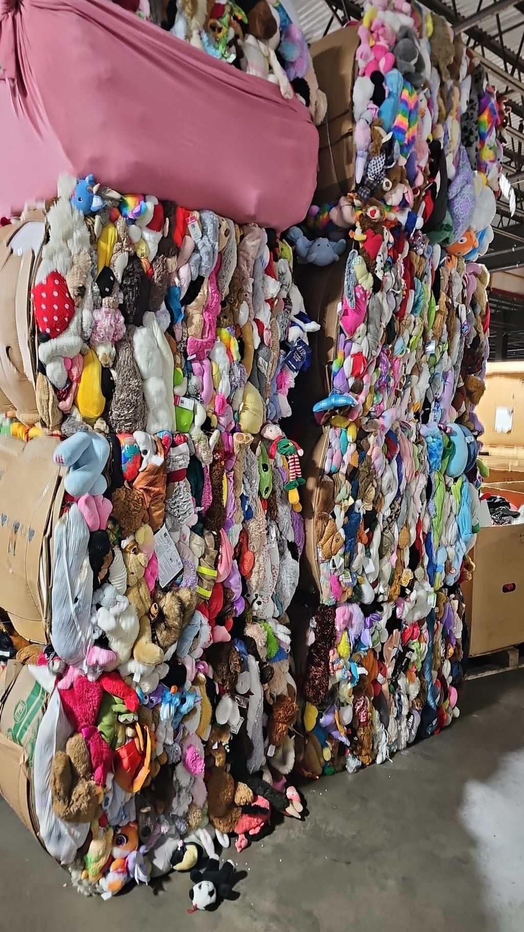 A large pile of stuffed animals stacked on top of each other in a warehouse.