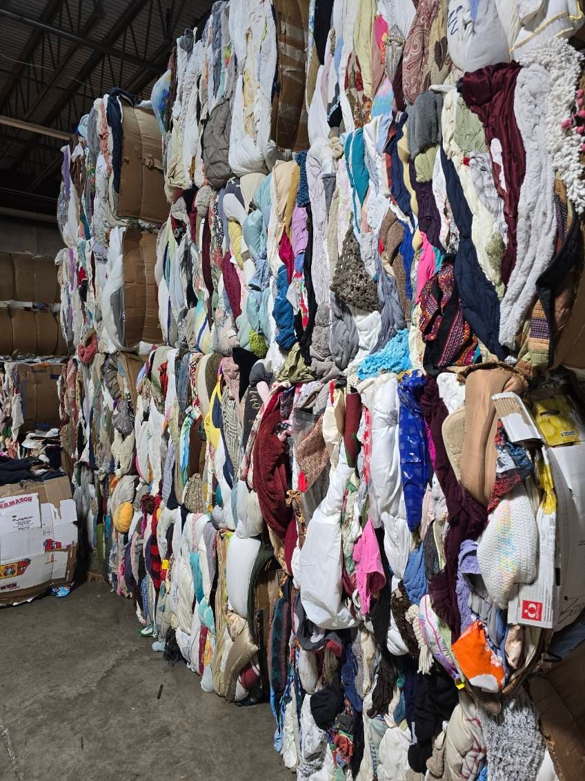 A large pile of clothes is stacked on top of each other in a warehouse.