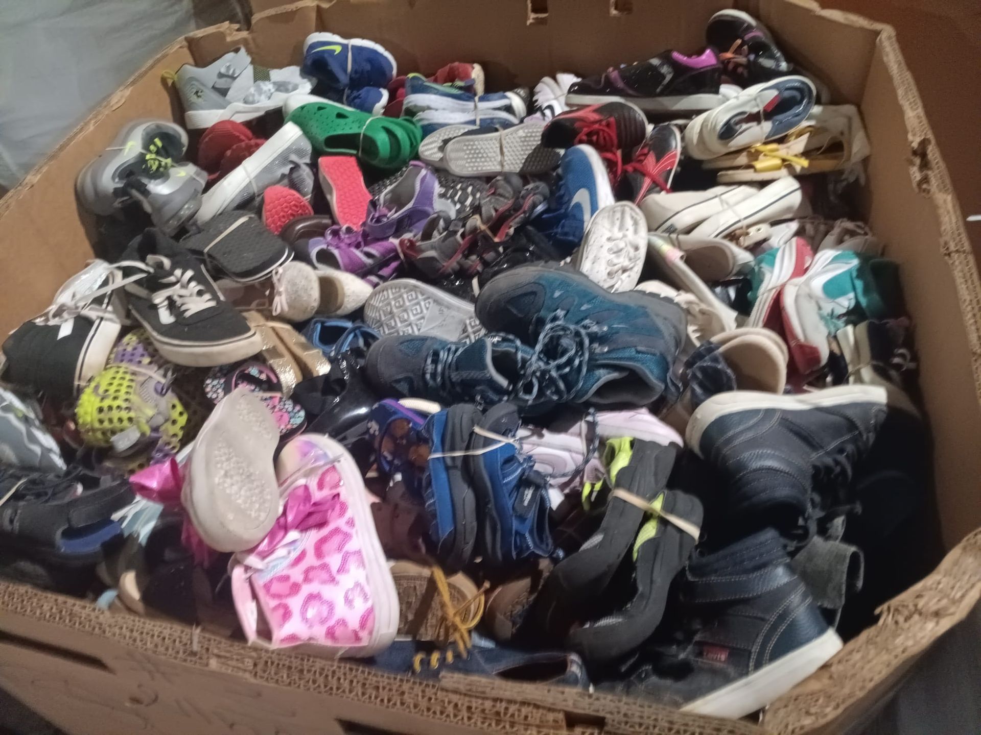 A cardboard box filled with a variety of shoes
