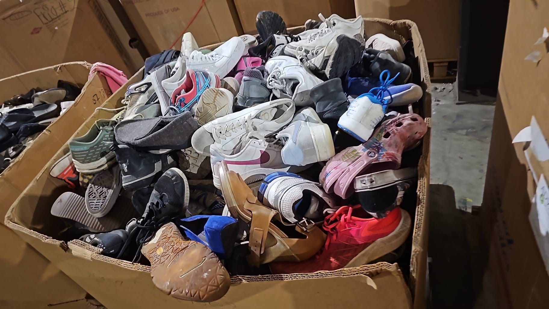 A cardboard box filled with a variety of shoes