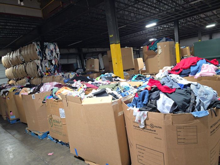 A warehouse filled with lots of cardboard boxes filled with clothes