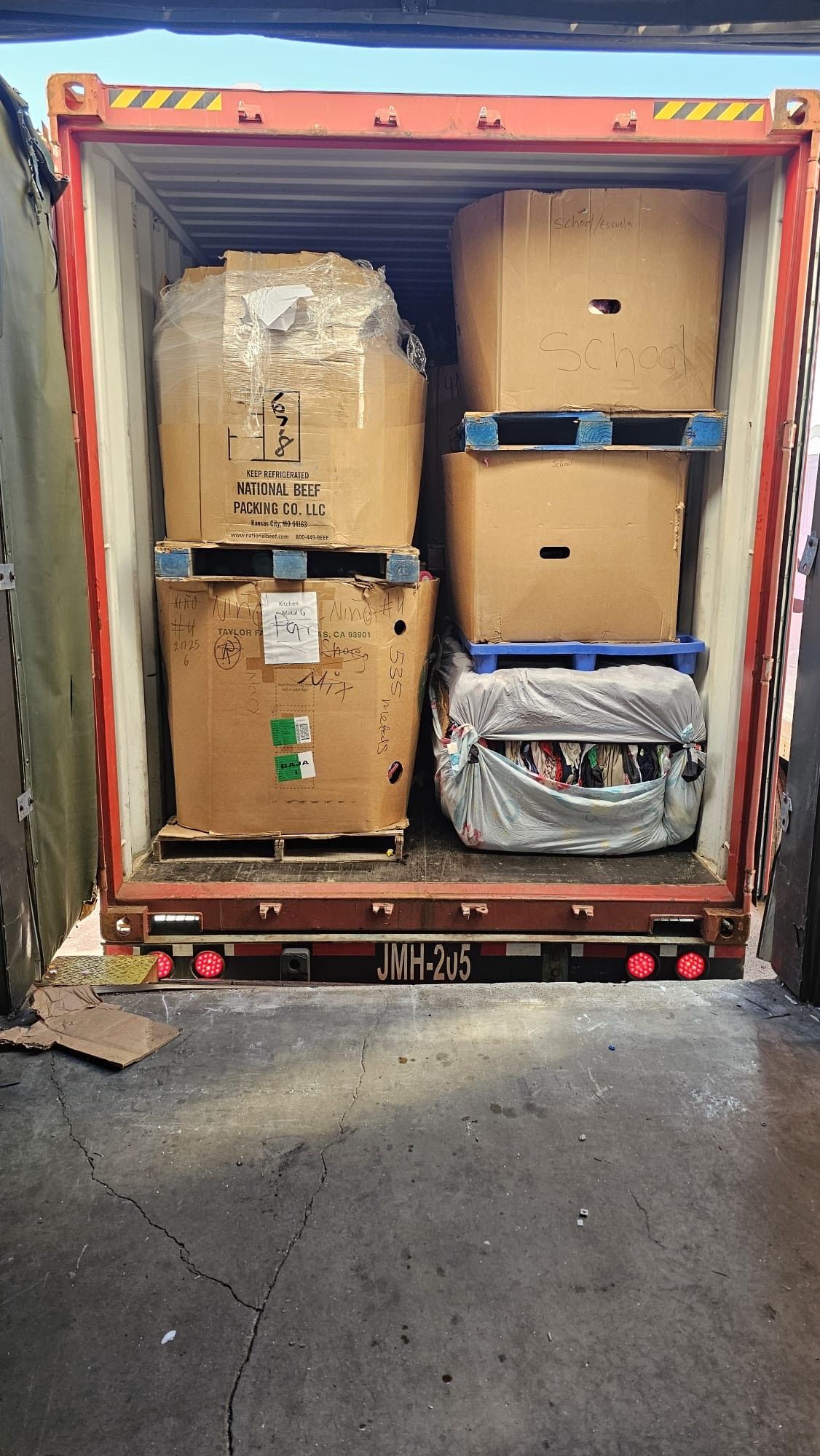 A shipping container filled with lots of boxes and pallets.