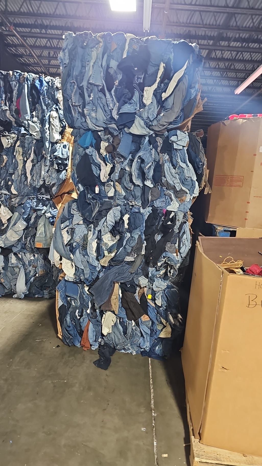 A pile of denim is sitting in a warehouse next to boxes.