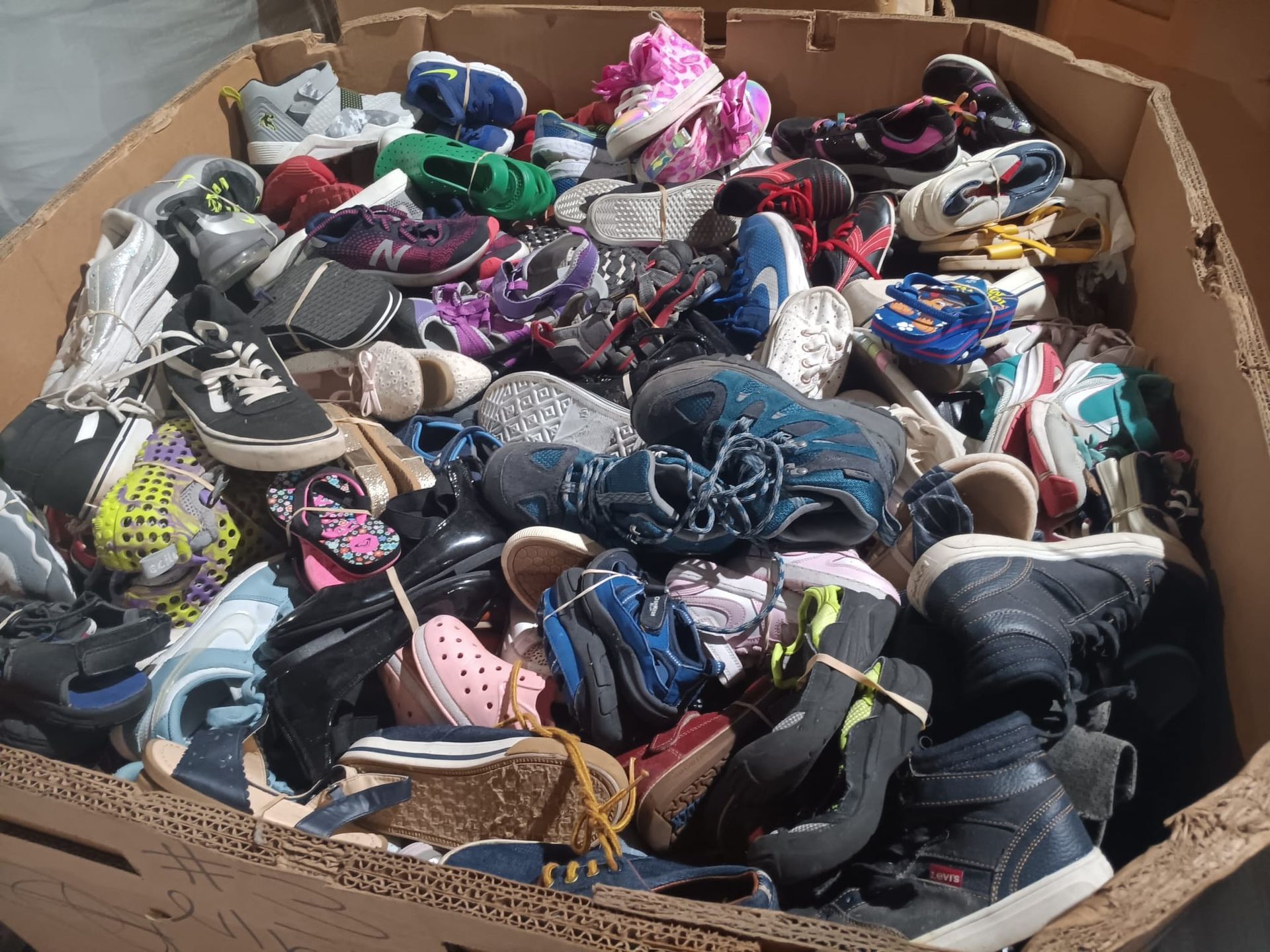A cardboard box filled with a variety of shoes