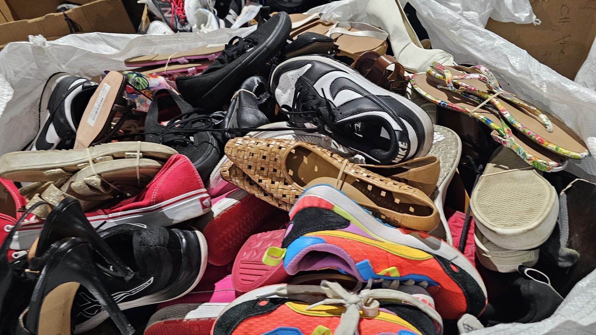 A pile of shoes and sandals in a box.
