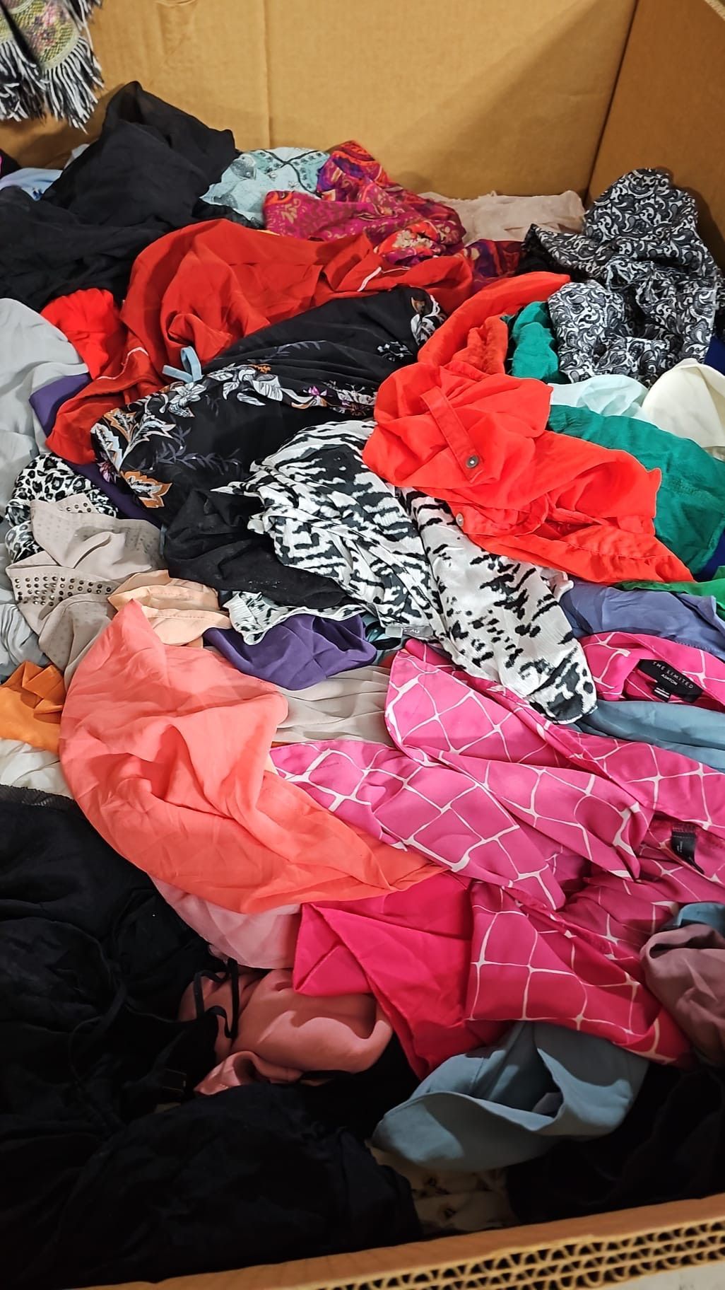 A pile of colorful clothes is sitting on top of a cardboard box.