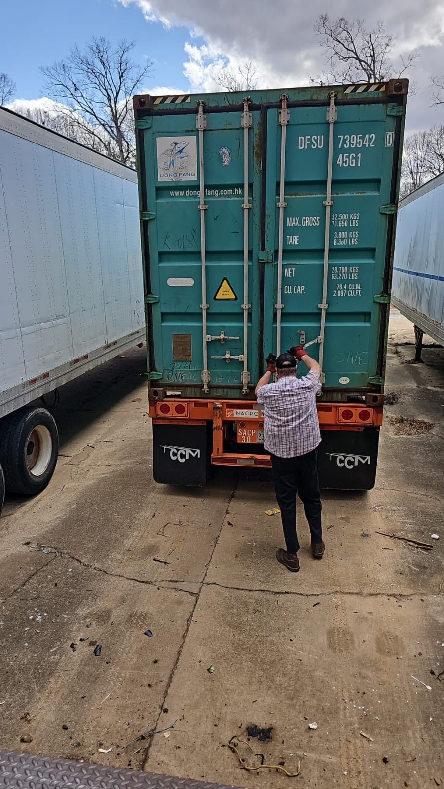 A man is standing next to a shipping container in a parking lot.