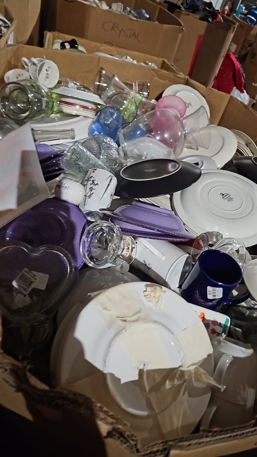 A cardboard box filled with plates , cups , and other items.