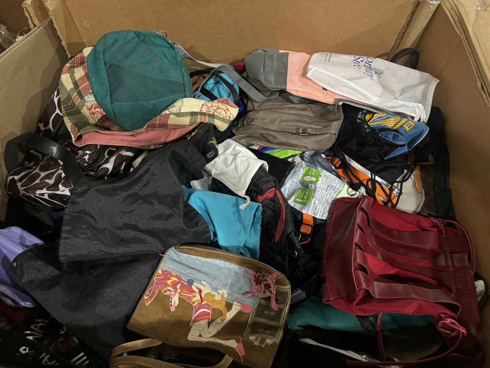 A cardboard box filled with a variety of bags and hats.