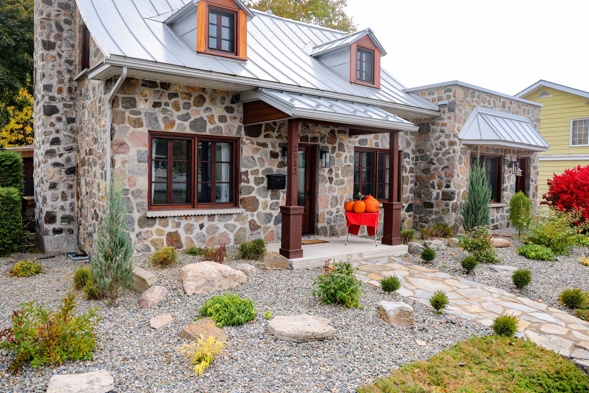 Une maison en pierre avec un toit en métal et un banc rouge devant.