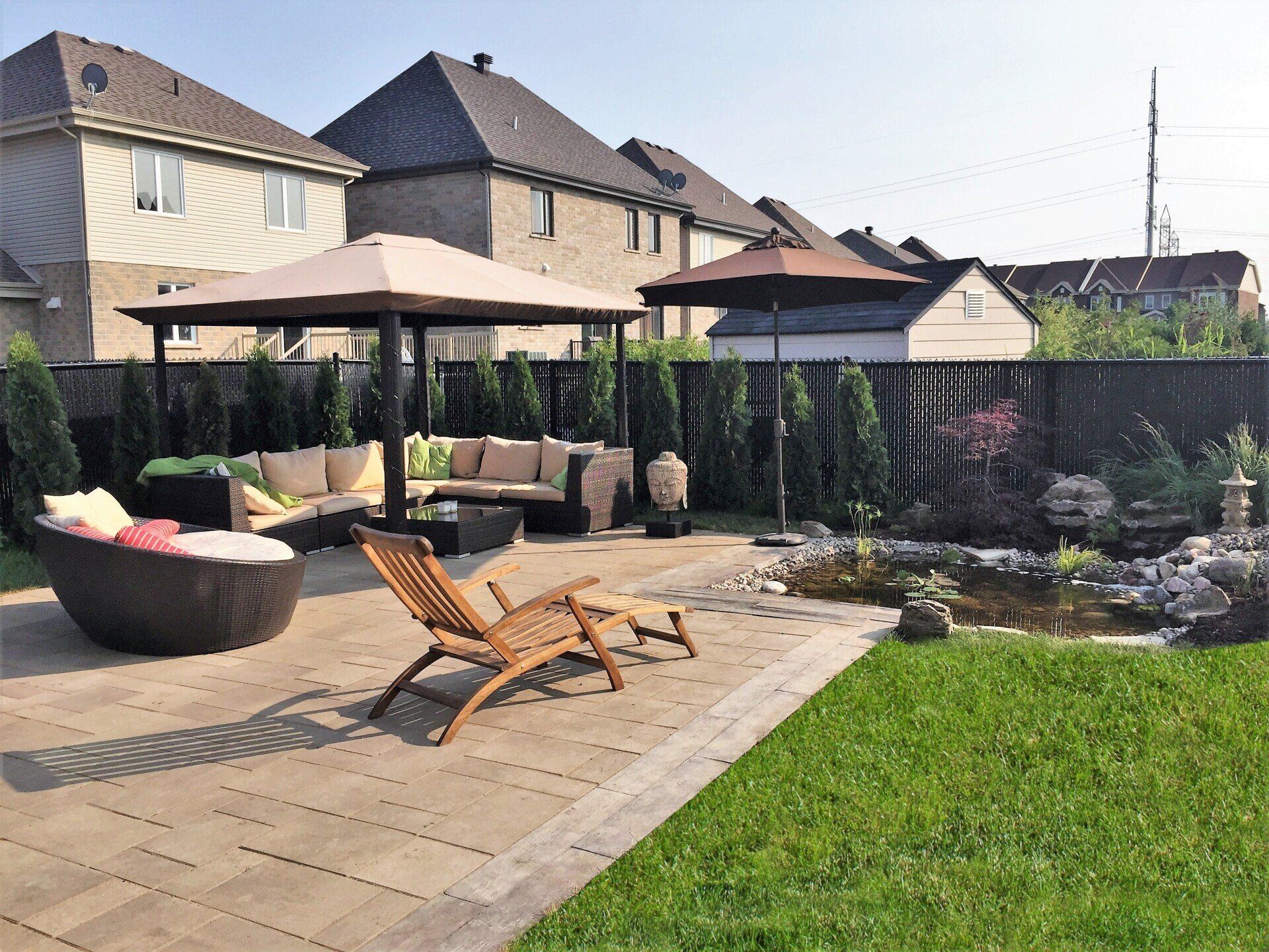 Une cour arrière avec un patio, des chaises, des parasols et un canapé.