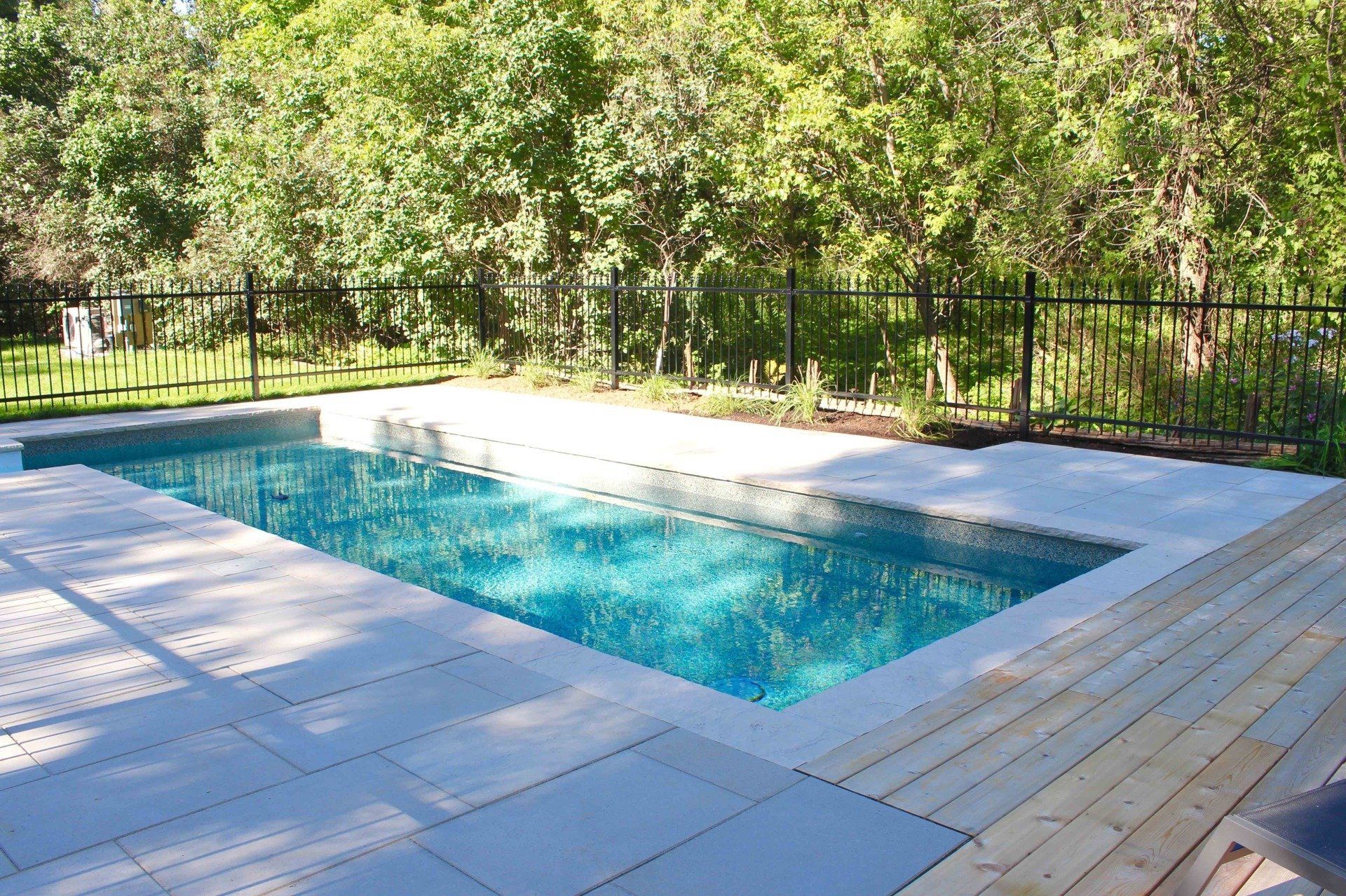 Une grande piscine est entourée d'arbres et d'une clôture