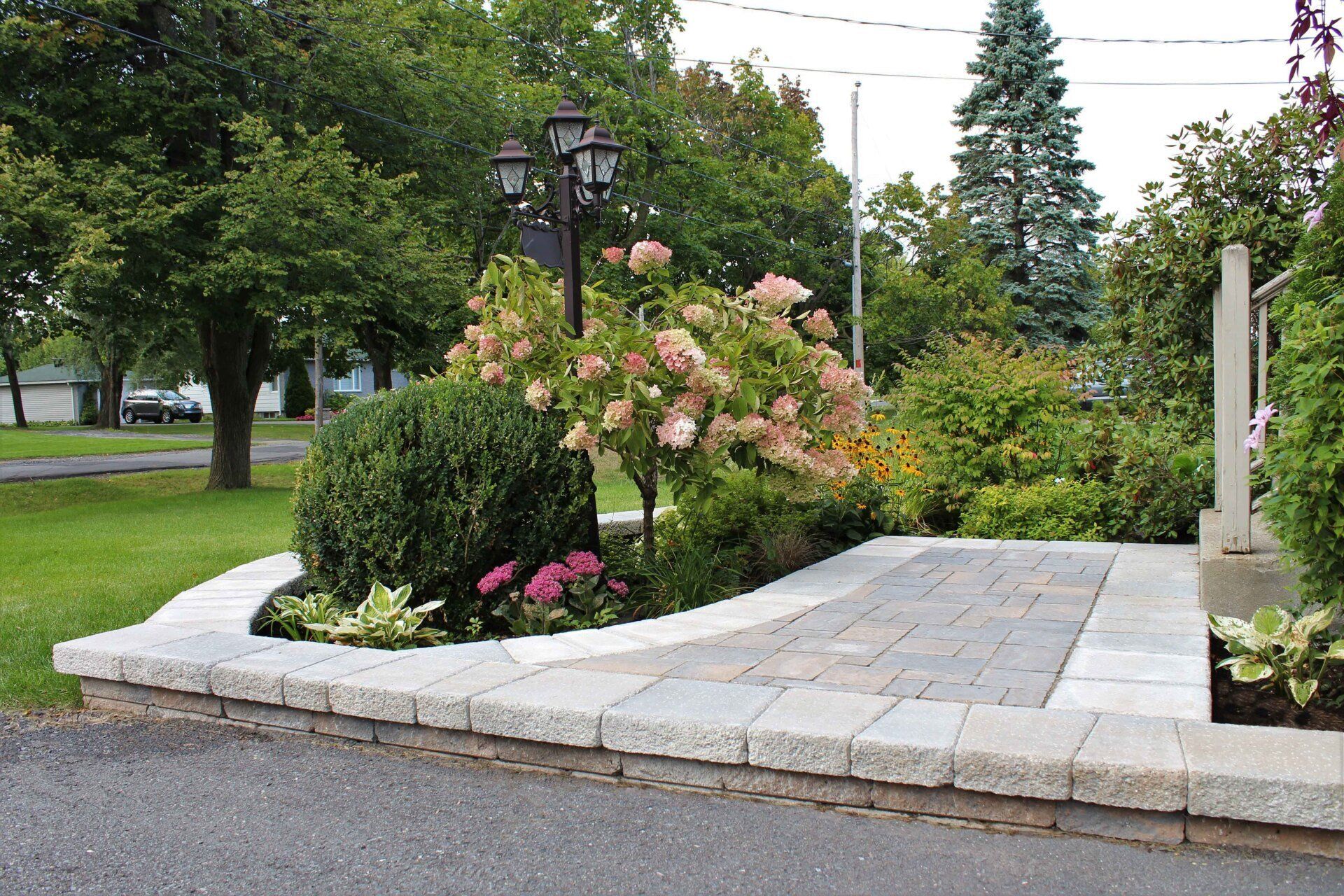 Une allée en briques menant à un jardin avec des fleurs et des buissons
